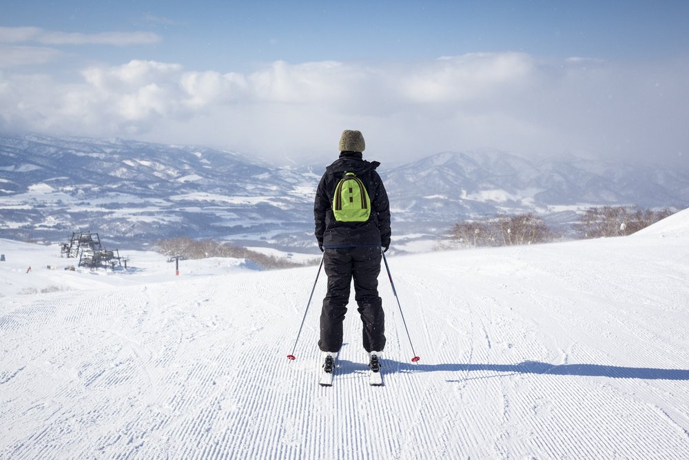 Back view of a female skier as she sets off down a freshly groomed ski slope in the light sno