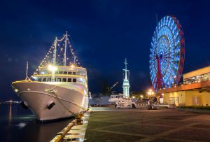 Cruise ship and Ferris wheel of Kobe Harborland in port of Kobe with skyline at dusk, Kansai