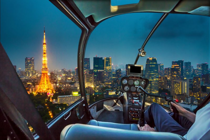 Helicopter flying on Tokyo Skyline at dusk with illuminated Tokyo Tower, icon and landmark of Minato Distric in Tokyo, Japan